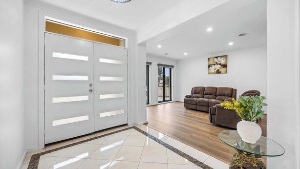 A spacious living area with a modern design, featuring a glass coffee table, a brown sofa, and a decorative vase. - The Canadian Escape, Ballarat - Up to 10 guests! (Canadian)