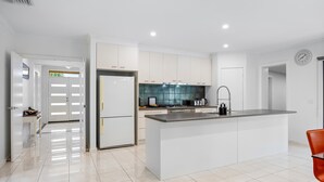 A modern kitchen with white cabinets, a central island, and a stainless steel sink. - The Canadian Escape, Ballarat - Up to 10 guests! (Canadian)