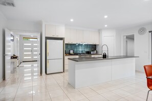 Une cuisine moderne avec des meubles blancs, un îlot central et un évier en acier inoxydable.