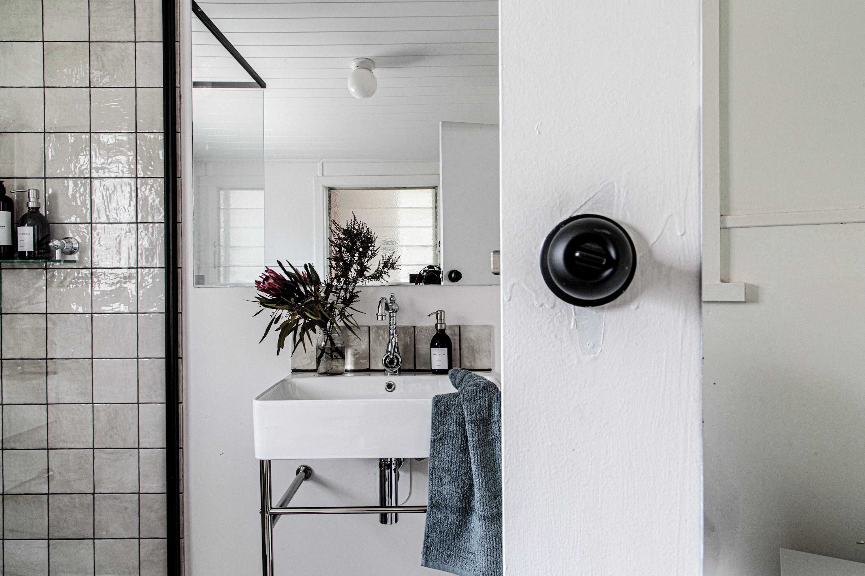 A bathroom with a white sink, a mirror, and a towel hanging on the wall.