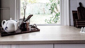 A kitchen with a window, a tea set, a pepper grinder, and a wooden cutting board. - Kent House (Ballarat Central)
