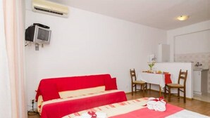 A room with two beds, a small table with chairs, a TV, and an air conditioner.