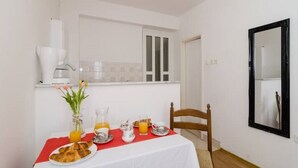 A small dining area with a table set for breakfast, a coffee maker, and a mirror on the wall.