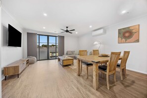 A modern living room with a dining area, a flat-screen TV, ceiling fan, and a large window. - Ballarat Bliss at Kevlar (Canadian)