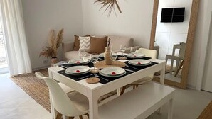 A dining area with a white table set for four, surrounded by white chairs. - Luxury 2 bedroom sleeps 6, balcony, city center, ideal to visit Cinque Terre (La Spezia)