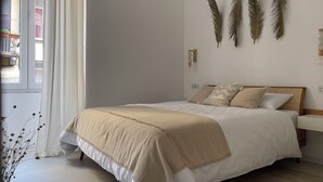 A bedroom with a bed, a bedside table, a hanging light fixture, and a window with curtains. - Luxury 2 bedroom sleeps 6, balcony, city center, ideal to visit Cinque Terre (La Spezia)