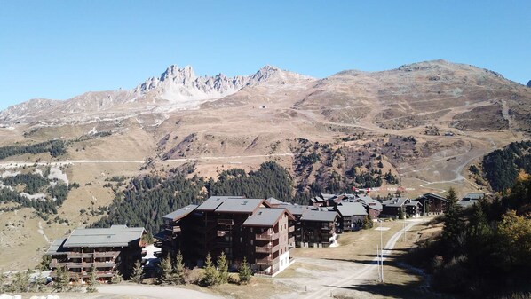 A mountain lodge with multiple buildings, a ski slope, and a clear view of the surrounding mountains.
