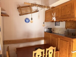 Une cuisine en bois au style rustique, comprenant une table et des chaises en bois, un luminaire suspendu et un panneau décoratif mural.