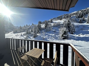A wooden deck with a table and chairs overlooking a snowy mountain landscape.