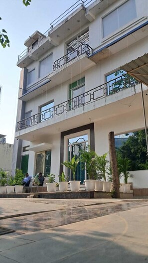 A multi-story building with balconies, large windows, and potted plants.