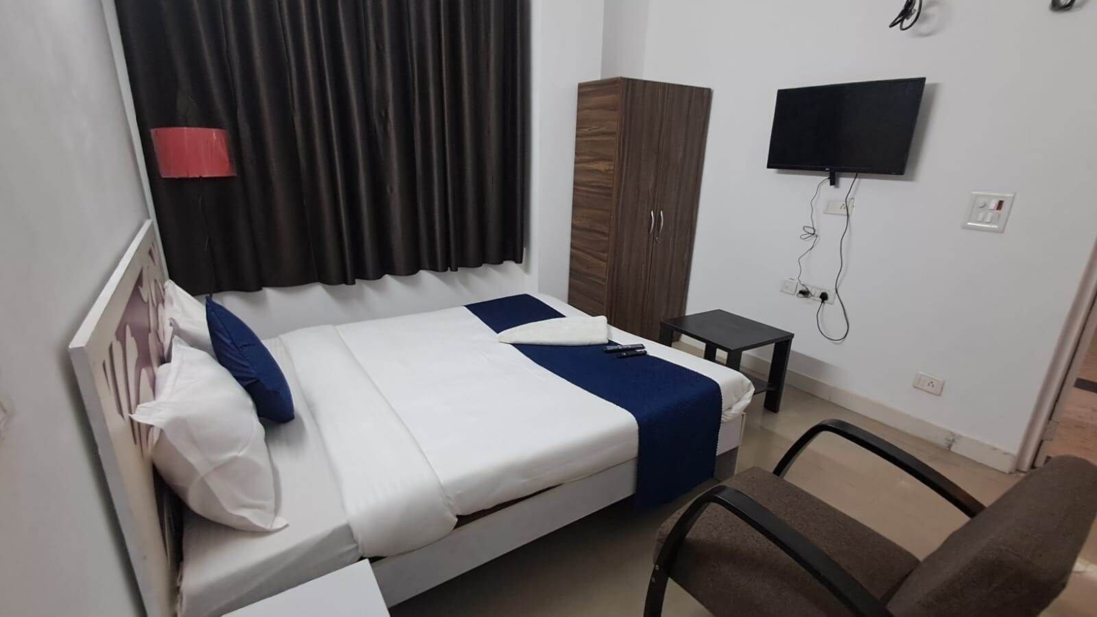 Een hotelkamer met een bed, een kledingkast, een televisie en een klein tafeltje.