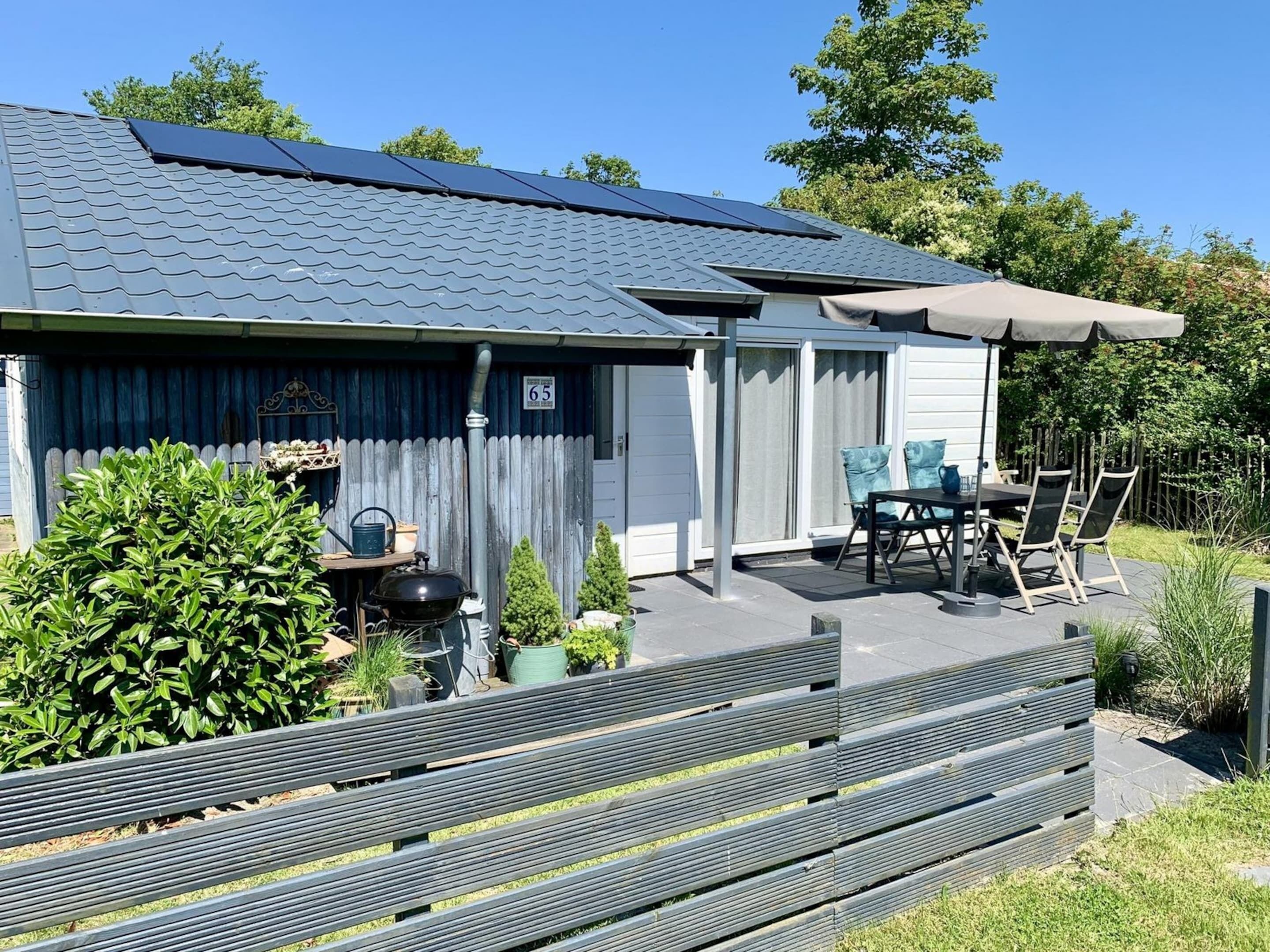 Une maison dotée d’un patio couvert, d’un barbecue et d’une plaque portant le numéro 65.