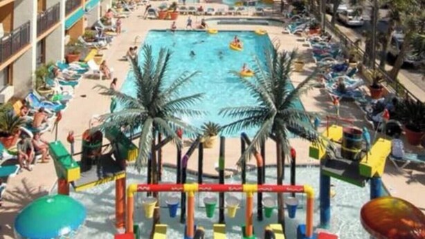 A resort with a large pool, palm trees, and a view of the beach. - Cozy 1-bedroom condo with AC, WiFi in Terrific Myrtle Beach (Myrtle Beach)