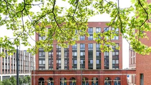 A multi-story building with a brick facade, large windows, and a series of arched doorways at the ground level. - Student Only Merchant Studios in Glasgow (Glasgow)