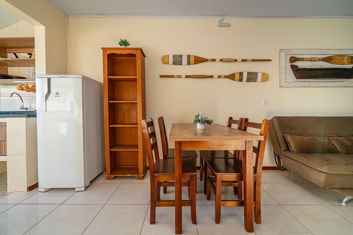 A dining area with a wooden table and chairs, a white refrigerator, a wooden cabinet, and a couch.