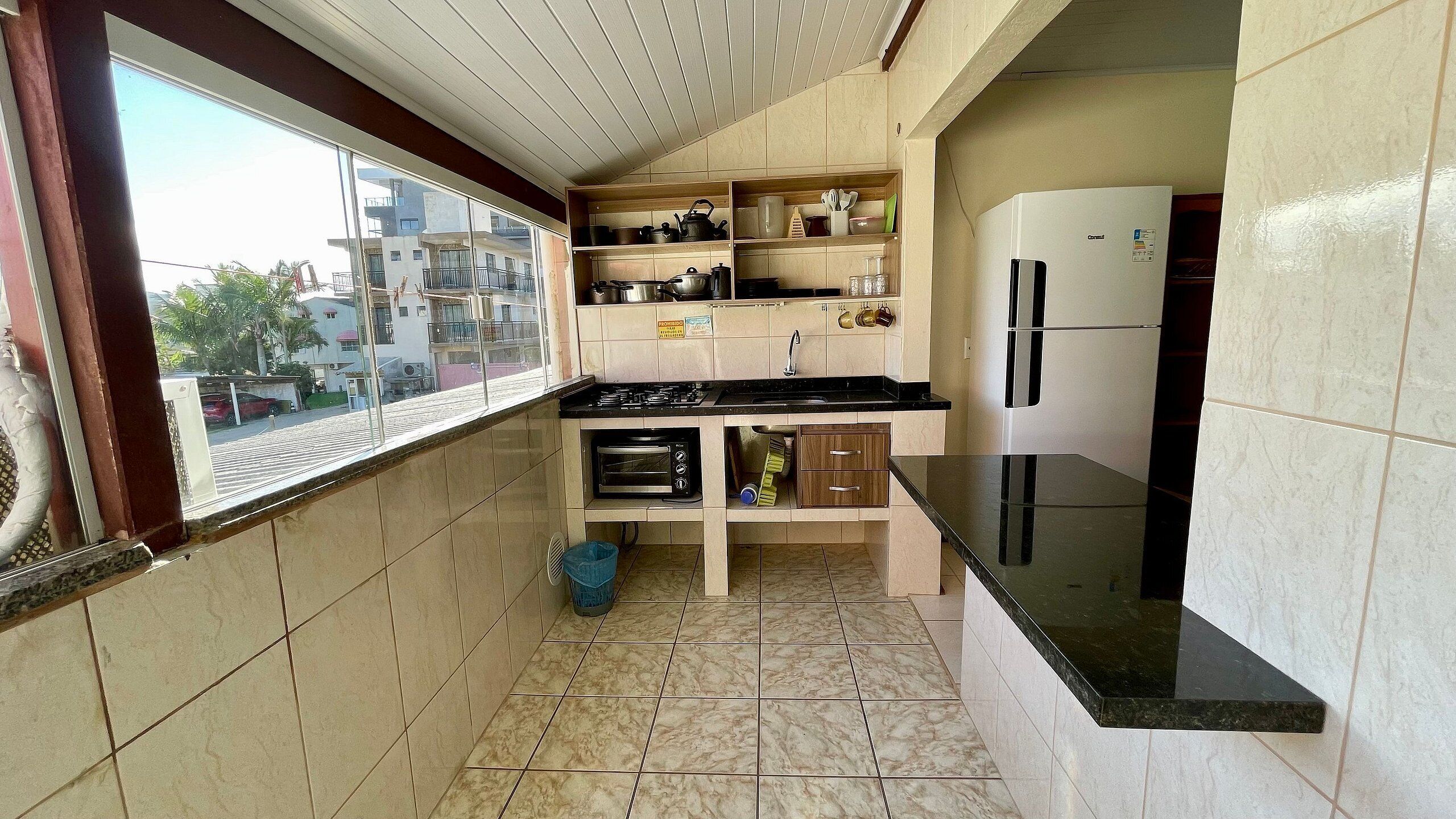 A compact kitchen with a window, a stove, a sink, and a refrigerator.