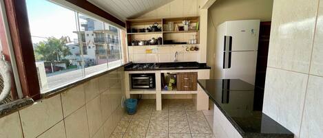 A compact kitchen with a window, a stove, a sink, and a refrigerator.