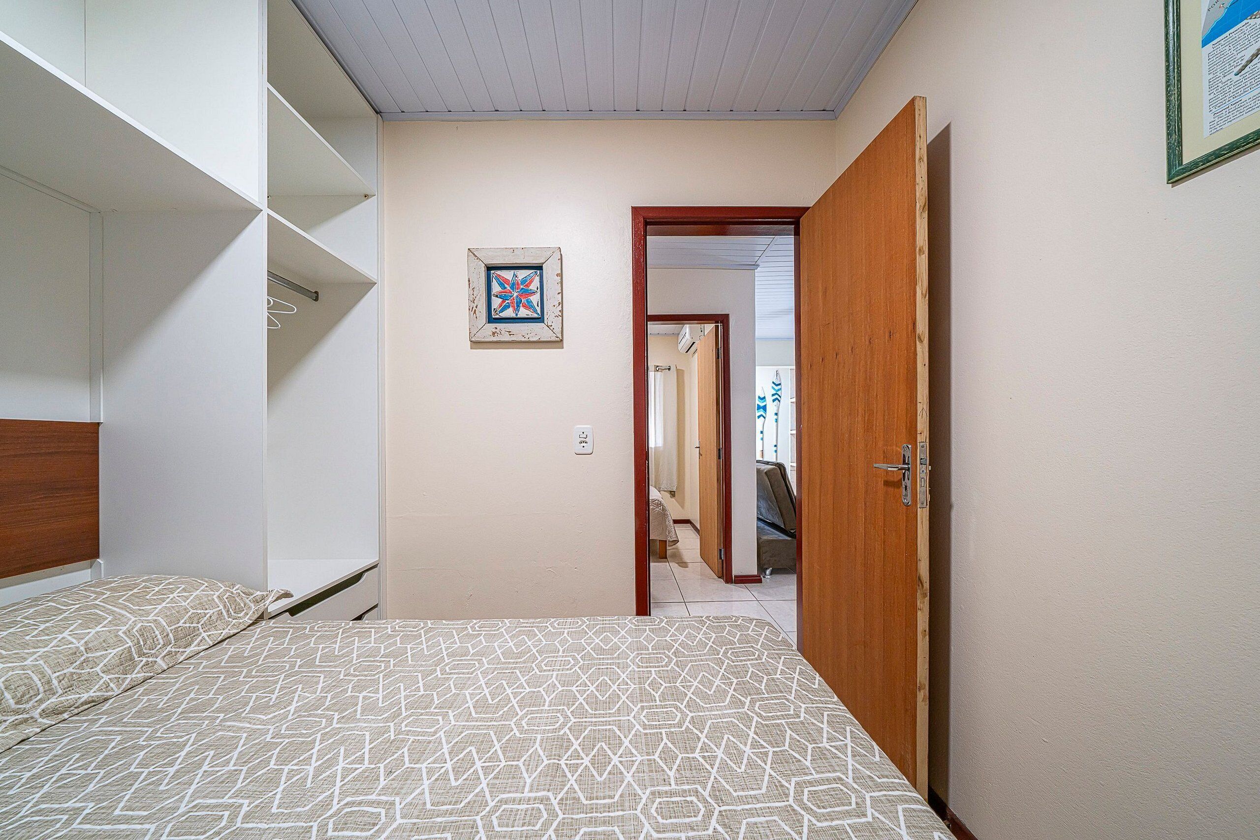Un dormitorio con una cama, un armario y una puerta que da a otra habitación.