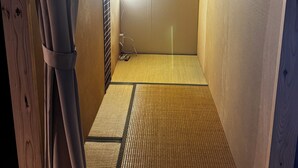 A room with a tatami mat floor, wooden walls, and a sliding door.