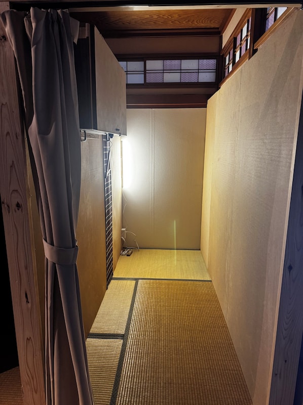 A room with a tatami mat floor, wooden walls, and a sliding door.