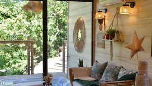 A cozy interior with a wooden ceiling, a sofa, a small table, and a star decoration on the wall. - Lodge Nid Perché - Les Cabanes de Provence (Lafare)