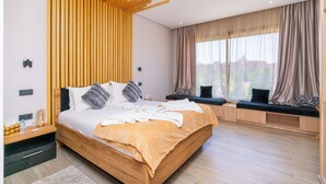 A modern bedroom with a wooden bed, built-in seating, and large windows.