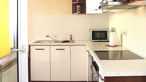 Cuina compacta amb armaris blancs, microones, rentapelats i fogó.