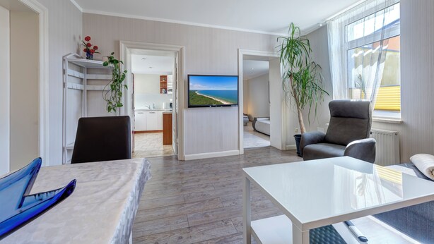 Habitació d'hotel moderna amb sòl de fusta, televisió de pantalla plana, taula de dinar, sofà i cadira.