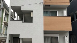 Un edificio residencial de varios pisos con balcones, un garaje y una caja eléctrica visible.