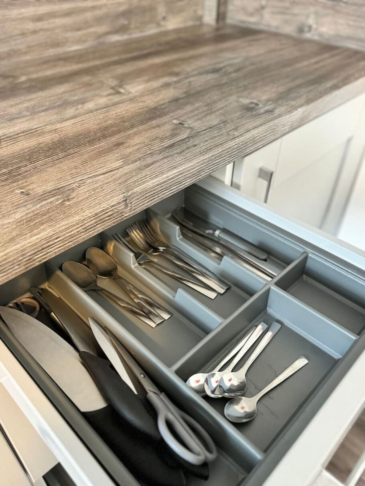 A drawer with neatly organized kitchen utensils including forks, knives, and spoons.