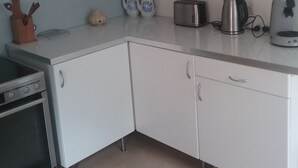 A kitchen with white cabinets, a stove, a toaster, a kettle, and a coffee maker. - Temporary living  (Freiburg im Breisgau)