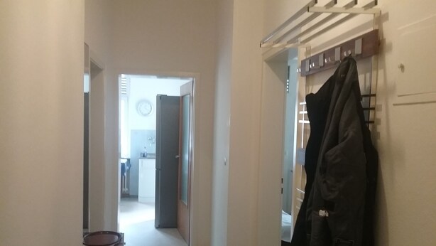 A hallway with a coat rack, a door leading to a kitchen, and a small rug on the floor. - Temporary living  (Freiburg im Breisgau)