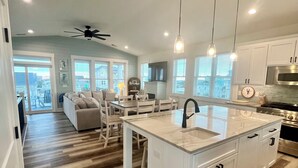 A modern kitchen with white cabinetry, a central island with a sink, and pendant lighting.