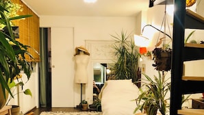 A bedroom with a bed, a wooden floor, a patterned rug, and several potted plants. - Charming family home near Sacrée Coeur  (Ile de France, Paris)