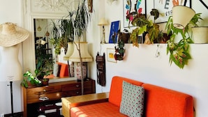 A cozy living room with a sofa, a coffee table, and a fireplace. There are several potted plants and decorative items on the walls. - Charming family home near Sacrée Coeur  (Ile de France, Paris)