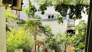 A covered patio area with a table and chairs, surrounded by potted plants and a stone-tiled floor. - Charming family home near Sacrée Coeur  (Ile de France, Paris)