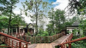 A wooden bridge with railings leading to a building surrounded by trees. - Emei Mountain Wannian Xueya Fang Hotel (Emeishan City)