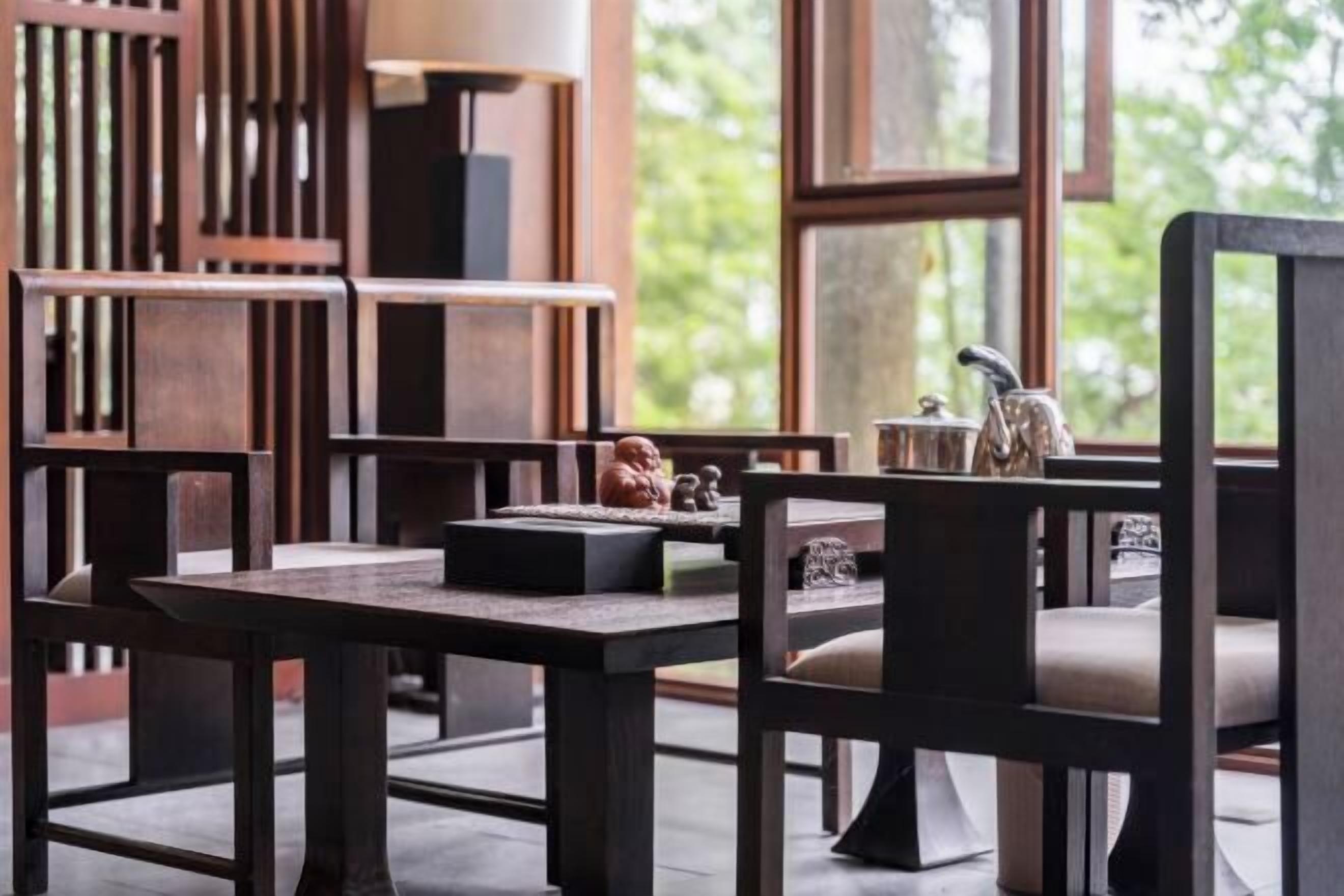 A modern dining area with wooden furniture and a view of greenery outside.