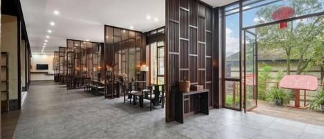 Un vestíbulo espacioso de diseño moderno, con una larga recepción, zona de estar y grandes ventanales que ofrecen vistas al exterior.