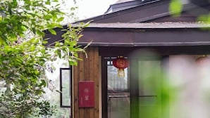 A traditional wooden building with a red signboard and a hanging ornament. - Emei Mountain Wannian Xueya Fang Hotel (Emeishan City)