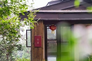 A traditional wooden building with a red signboard and a hanging ornament. - Emei Mountain Wannian Xueya Fang Hotel (Emeishan City)