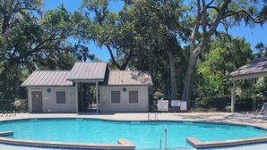 A swimming pool with a small building and a covered area, surrounded by trees. - Shipyard Resort - Brigantine Quarters (Hilton Head Island)
