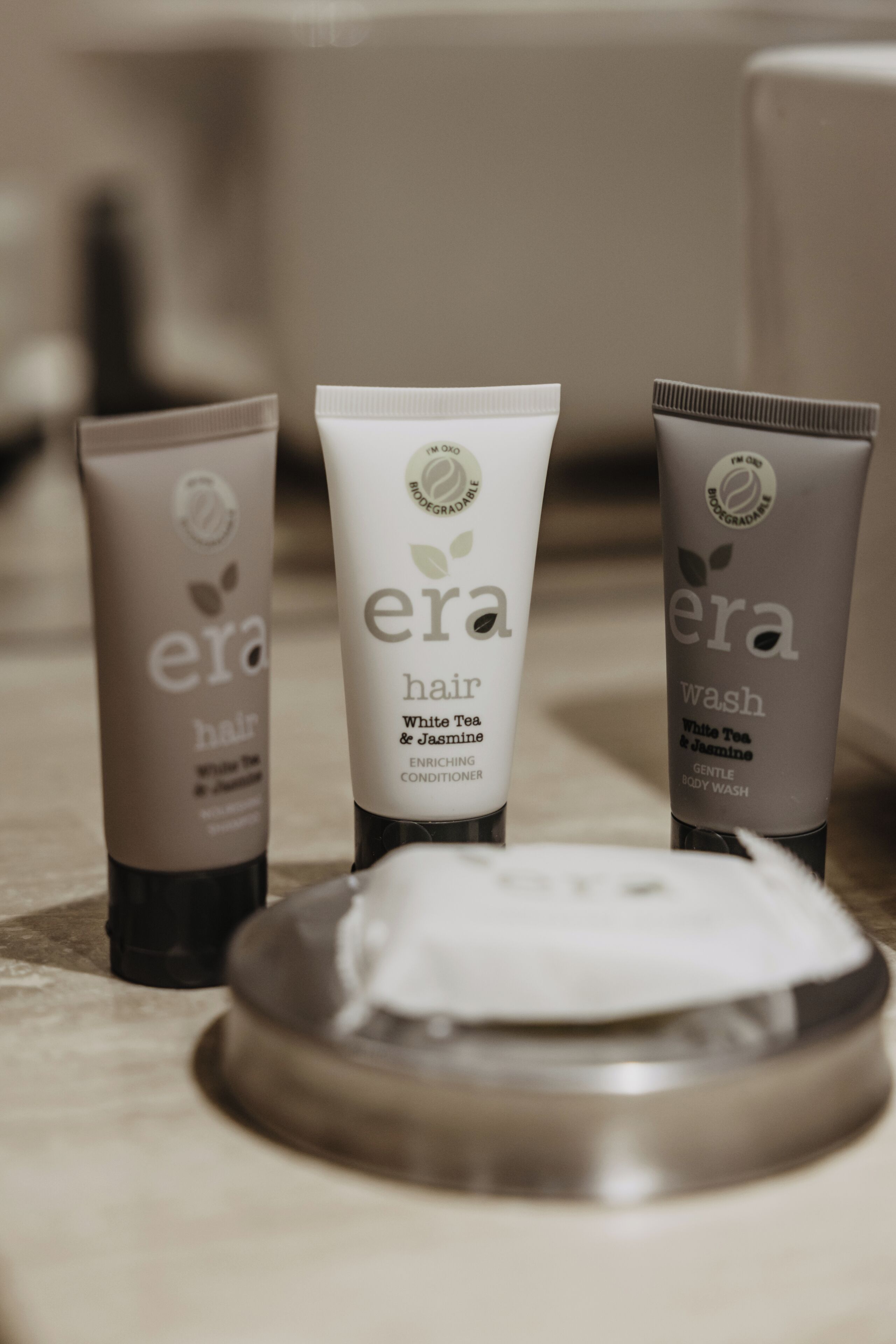 Tres botellas de productos 'era' para cabello y cuerpo sobre una superficie.