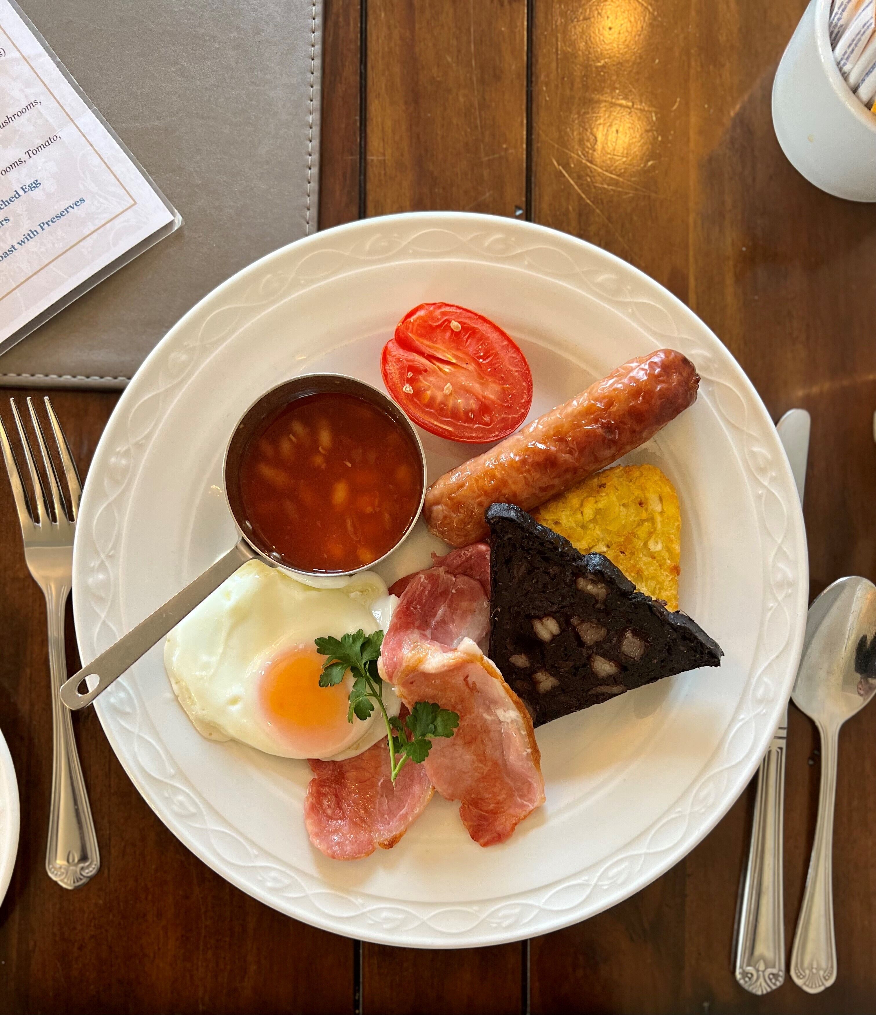 A plate of breakfast food including eggs, sausages, tomatoes, and toast.