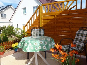 Un patio con una mesa cubierta con un mantel floral, una silla y un farol.