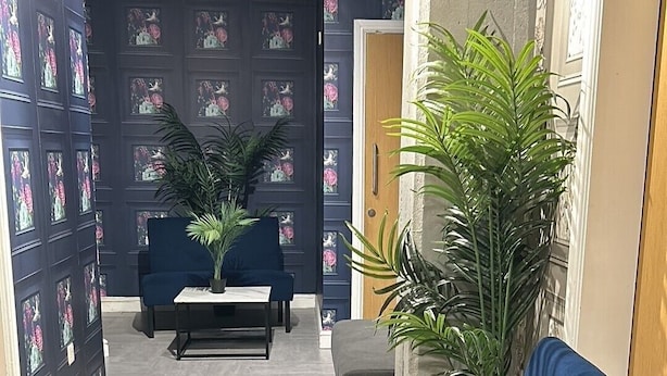 A reception area with a blue sofa, a coffee table, and potted plants. - Hillcrest Liverpool Central (Liverpool)