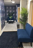 Un área de recepción con un sofá azul, una mesa de centro y plantas en macetas.