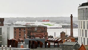 A view of a waterfront area with buildings, a large ship docked at the port, and a tall chimney. - Hillcrest Liverpool Central (Liverpool)