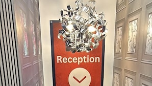 A reception area with a sign indicating the location, a staircase leading to an upper floor, and decorative wall panels. - Hillcrest Liverpool Central (Liverpool)