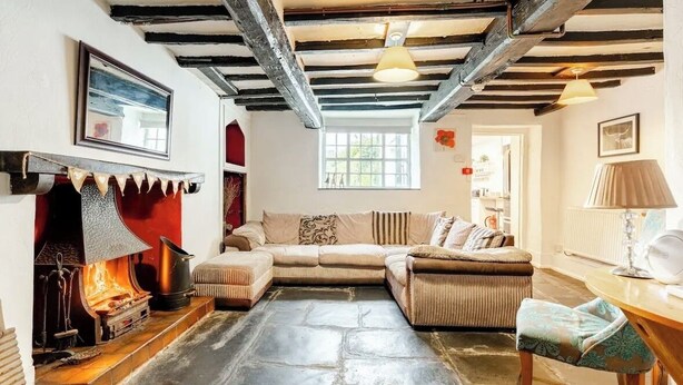 A cozy living room with a fireplace, a sofa, and a table with a lamp.
